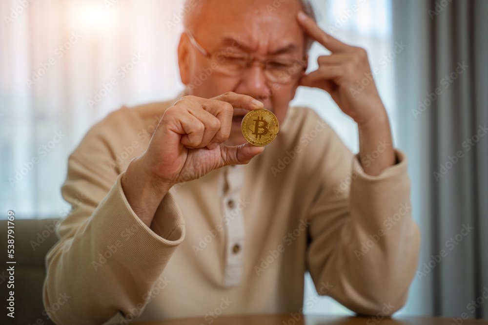 Senior man hold Bitcoin and stress due to losses from trading Bitcoin,Cryptocurrency trading concept.