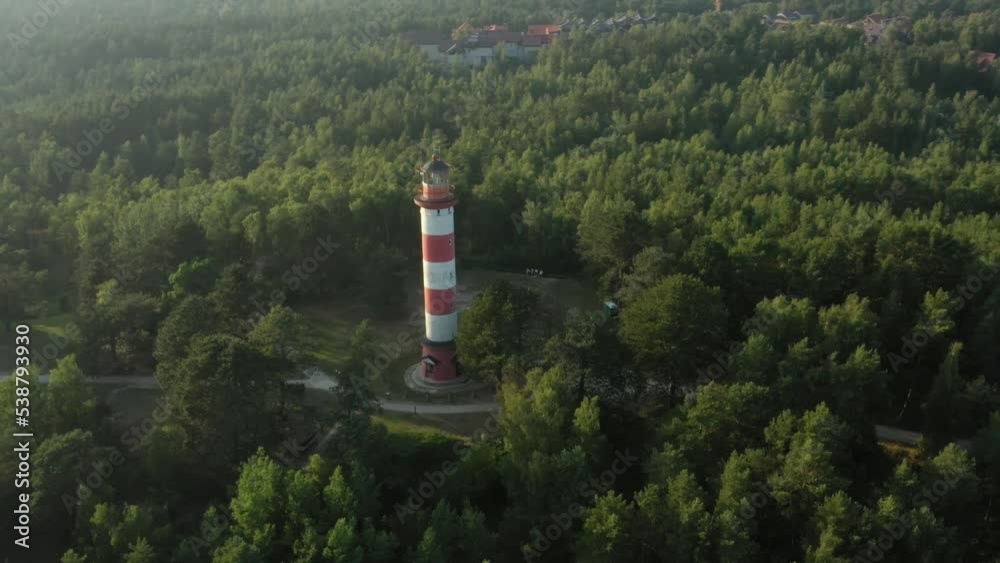 Close flyby of the lighthouse on the hill, lighthouse is located in the middle of forest on highest hill point, Baltic sea can be seen