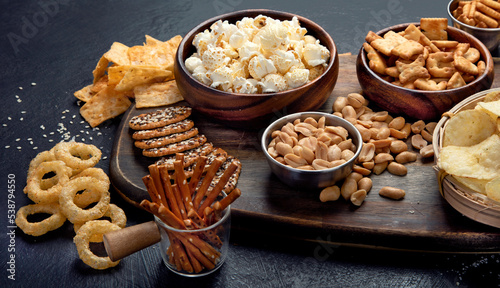 Assortment of salty snacks on dark background.