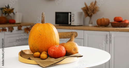 Tray with fresh pumpkins on dining table in kitchen