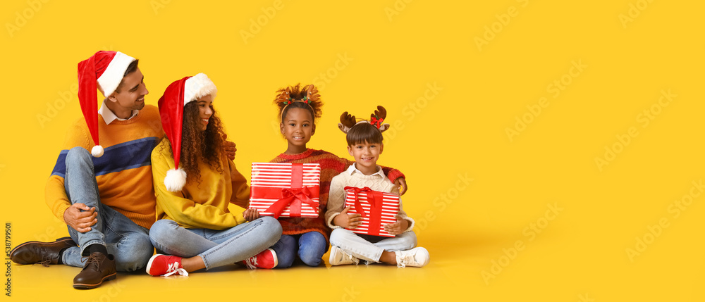 Fototapeta premium Happy family holding Christmas gifts on yellow background with space for text