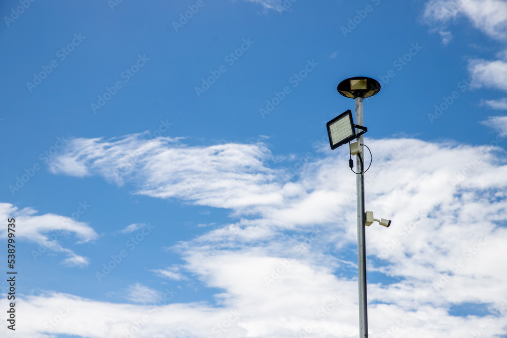 Public city light with solar panel powered on blue sky with clouds Public city light with solar panel powered on blue sky with clouds