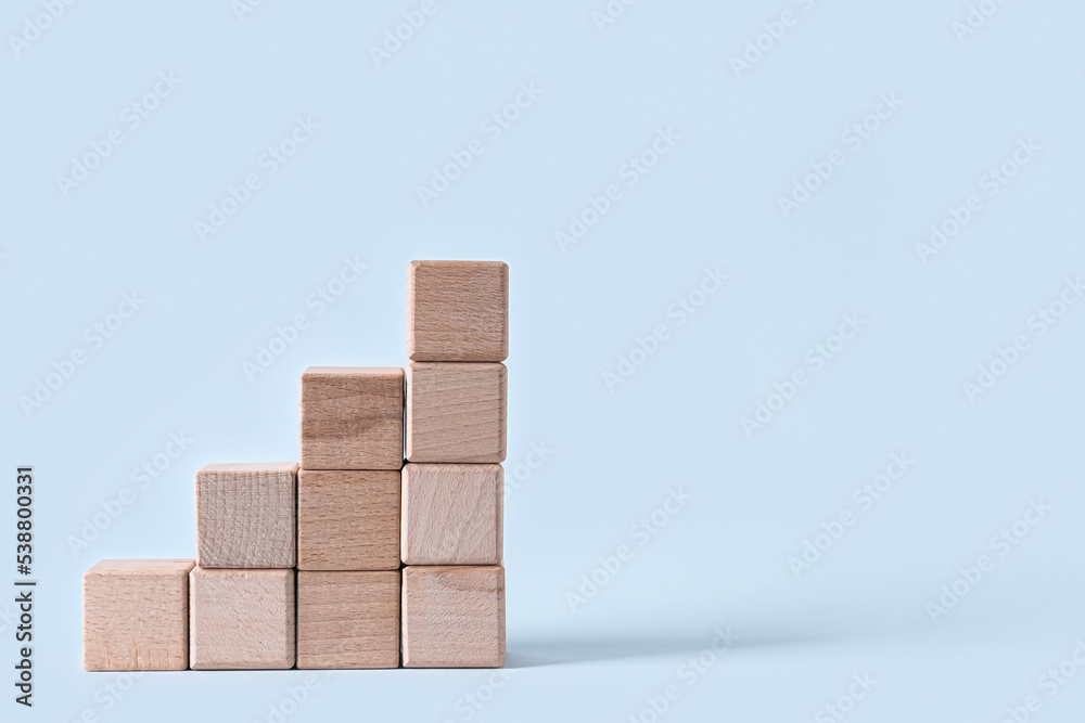 Ladder made of wooden blocks on light background