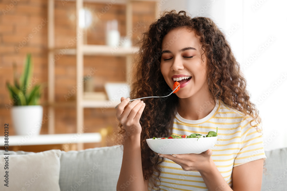 Young African-American woman eating healthy salad at home. Diet concept Young African-American woman eating healthy salad at home. Diet concept