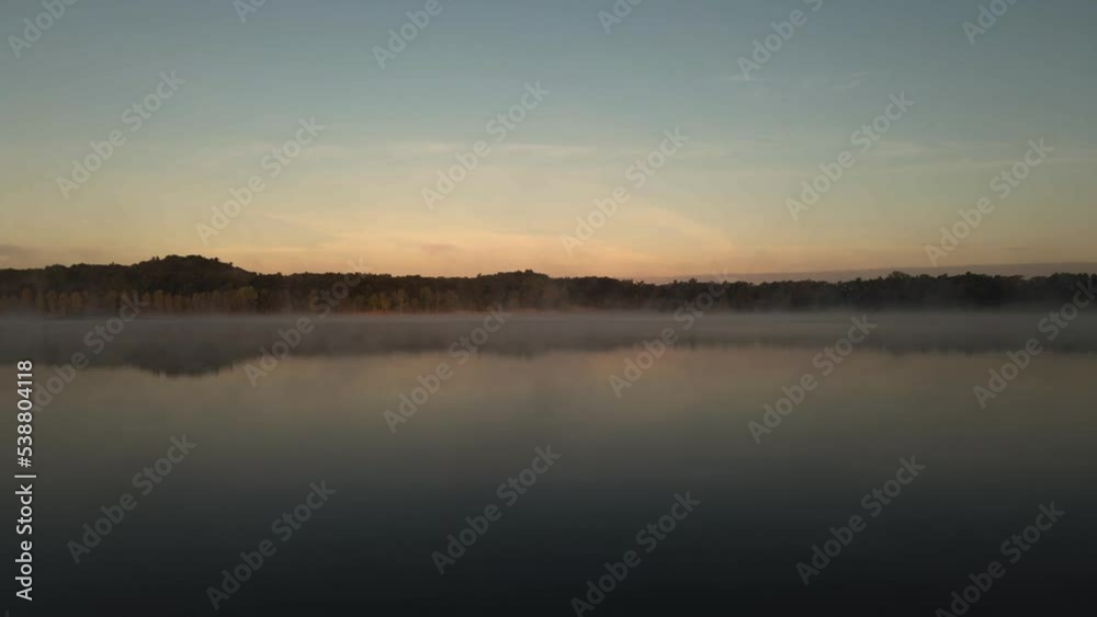 Near surface level flight across calm water. Heavy mist rising in cold air during sunrise. Near surface level flight across calm water. Heavy mist rising in cold air during sunrise.