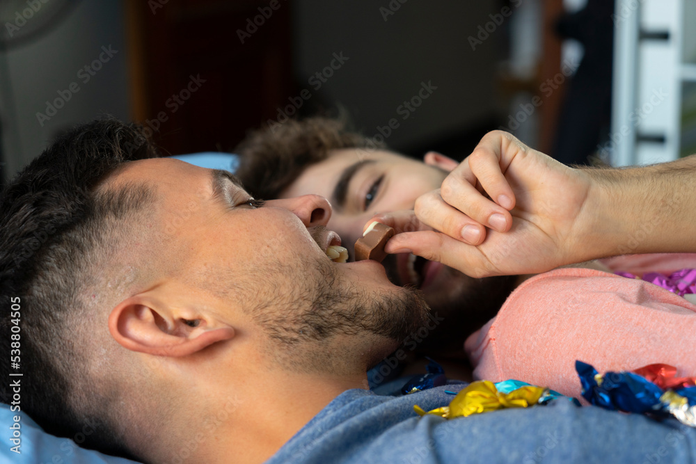 Gay couple lying on bed and looking each other Gay couple lying on bed and looking each other