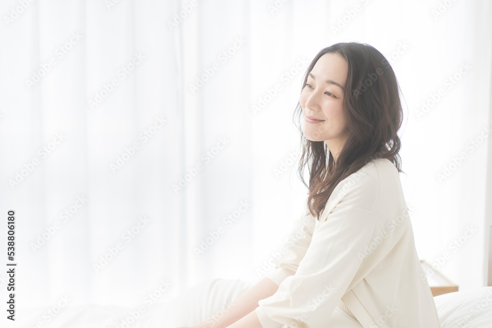 心地よい目覚め/微笑みながらベッドに座っている女性 心地よい目覚め/微笑みながらベッドに座っている女性