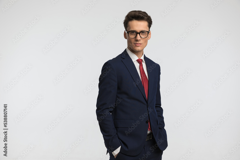attractive young guy with glasses in navy blue suit holding hands in pockets attractive young guy with glasses in navy blue suit holding hands in pockets