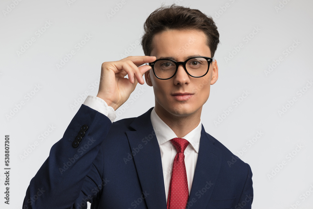 elegant businessman with red tie smiling and adjsuting eyeglasses