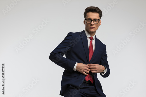 handsome businessman with glasses unbuttoning navy blue suit