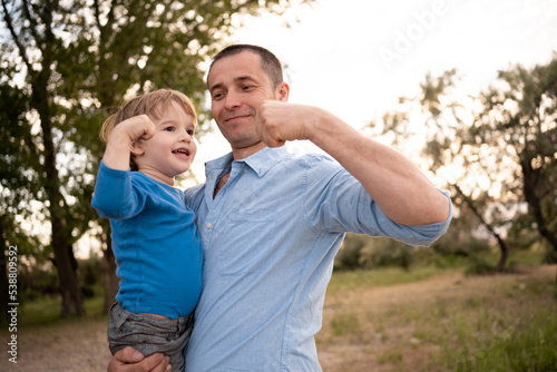 Father and son playing in the park at the sunset time. Smile child and dad happy together. People having fun on the field. friendly family and of summer vacation.