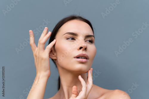 Close-up beauty portrait of a topless woman with perfect skin and natural make-up on light blue wall background