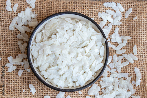 Flattened rice or beaten rice inside of carmic bowl, use in brakefast indian recipe poho over jute mat