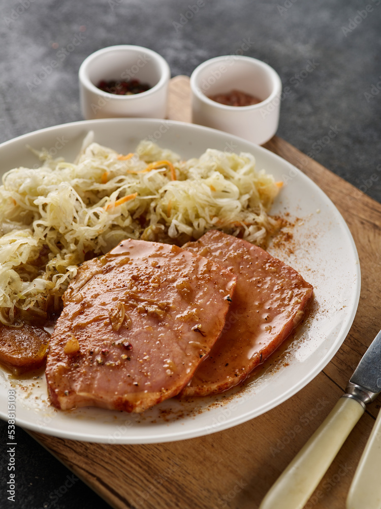 Backed Kasseler pork steak with sauerkraut. Smoked pork lion. Sliced smoked pork chop on wooden board Backed Kasseler pork steak with sauerkraut. Smoked pork lion. Sliced smoked pork chop on wooden board