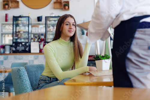 Happy waiter talking to female customer
