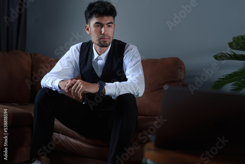 Portrait of a handsome, discreet Asian man sitting on the sofa using a computer