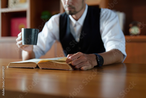 A portrait of a handsome and discreet Asian man sitting at his desk reading a book