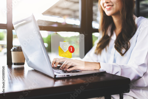 email marketing and inbox concept. Businesswoman checking e-mail on laptop with email inbox icon illustration. company sending many e-mails or digital newsletter to customers photo