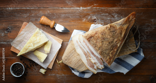Pecorino cheese, guanciale and pepper on wooden background. Top view, space for text..