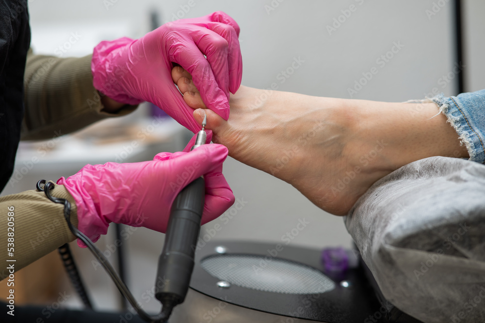 The master makes hardware pedicures to the client. Cuticle treatment. 