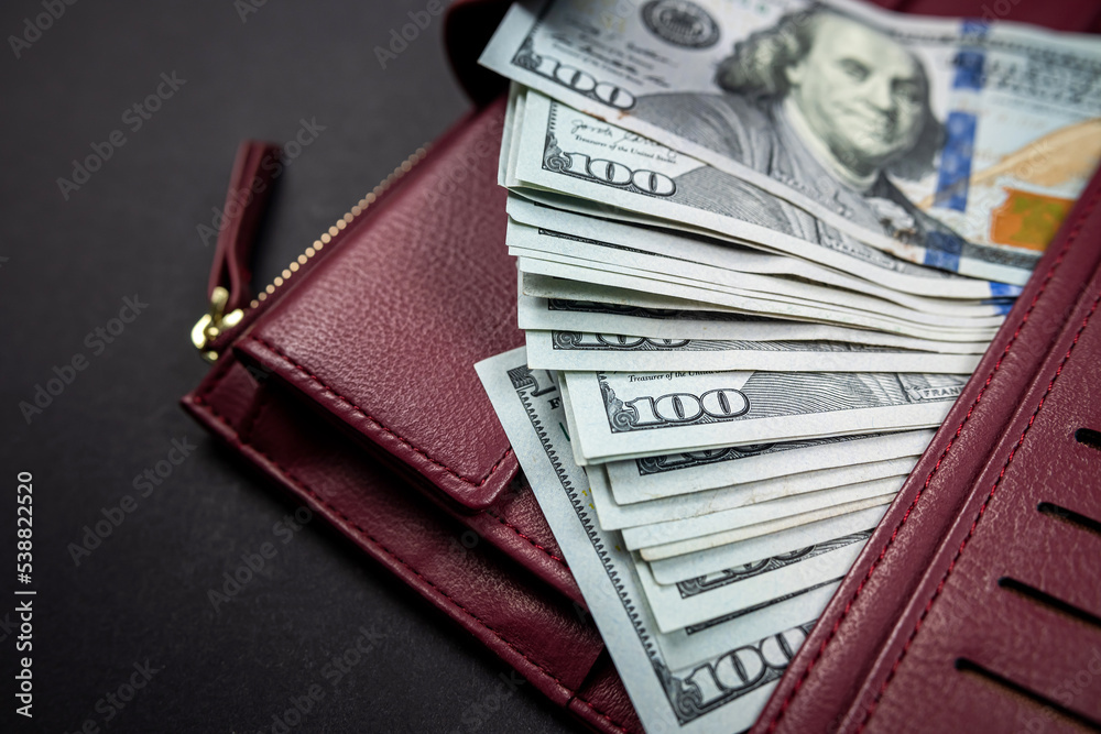 wallet full of money on wooden table one hundred US bills with portrait of President Franklin