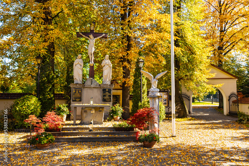 Field shrine aside St. Matthias church, kosciol sw. Macieja, over autumn colors in historic old town quarter of Andrychow in Poland photo