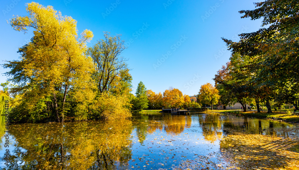 City park and lake with colorful fall trees leaf mosaic in historic old town quarter of Andrychow with Beskidy Mountains in background in Lesser Poland City park and lake with colorful fall trees leaf mosaic in historic old town quarter of Andrychow with Beskidy Mountains in background in Lesser Poland