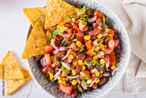 Mexican vegetable salad cowboy caviar and nachos in a bowl on the table. Top view. Closeup