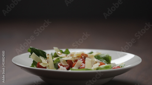 making salad pour dressing over in white bowl