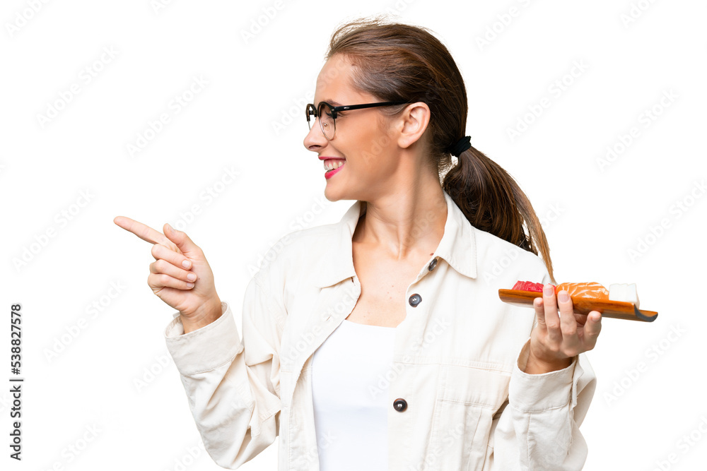 Young caucasian woman holding sashimi over isolated background pointing to the side to present a product Young caucasian woman holding sashimi over isolated background pointing to the side to present a product