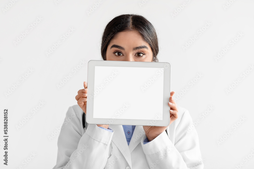 Young hindu lady doctor in coat show tablet with blank screen, isolated on white background Young hindu lady doctor in coat show tablet with blank screen, isolated on white background