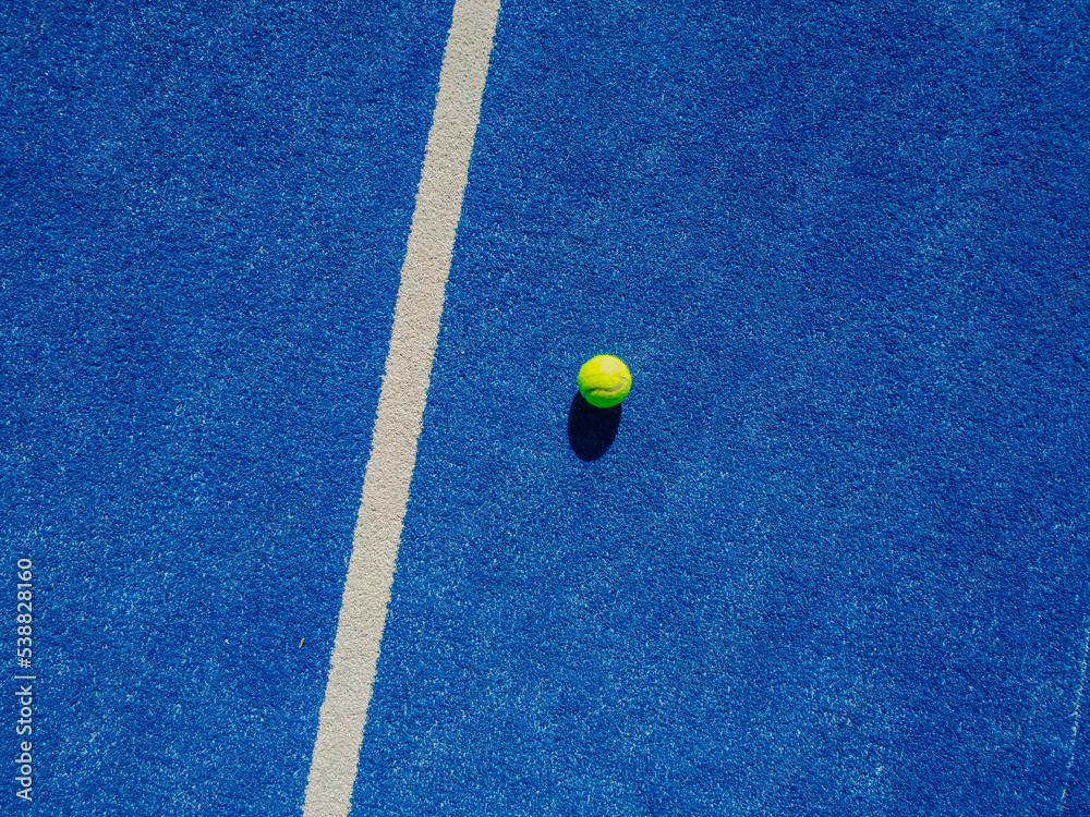 isolated ball on a blue paddle tennis court, drone aerial view