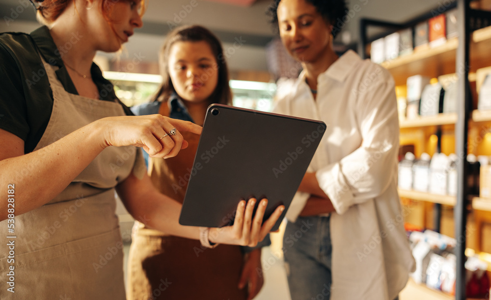 Grocery store manager using a digital tablet with her employees Grocery store manager using a digital tablet with her employees
