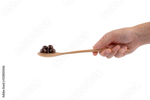 Hand and chocolate balls on wooden spoon on transparent background.