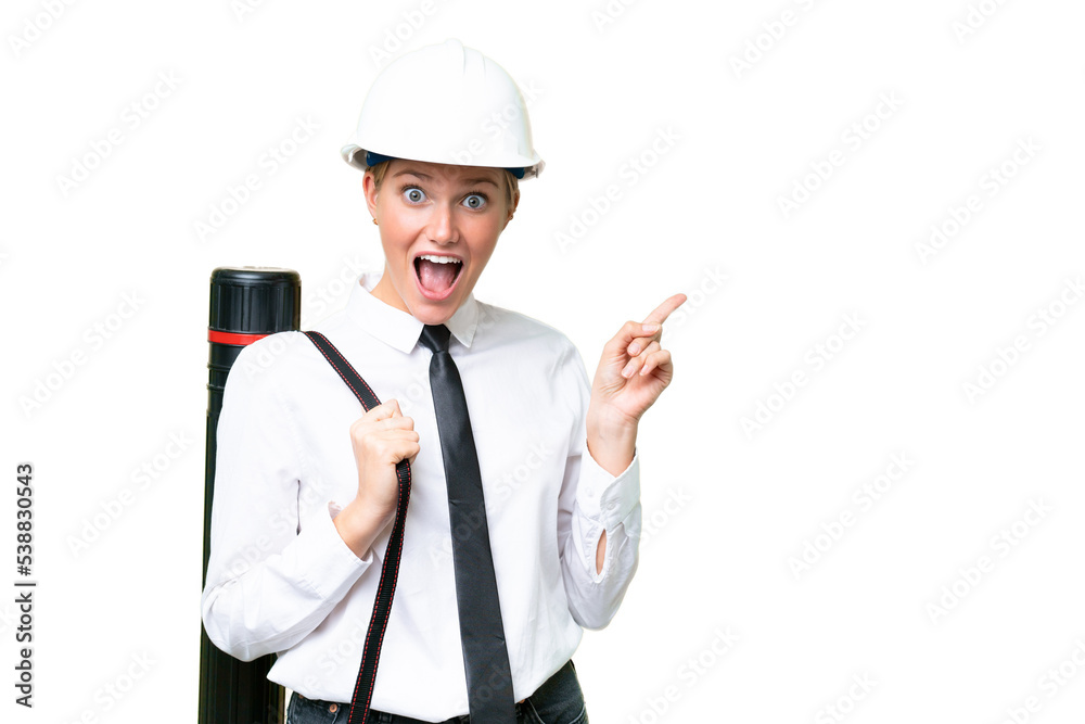Young architect caucasian woman with helmet and holding blueprints over isolated background surprised and pointing side Young architect caucasian woman with helmet and holding blueprints over isolated background surprised and pointing side