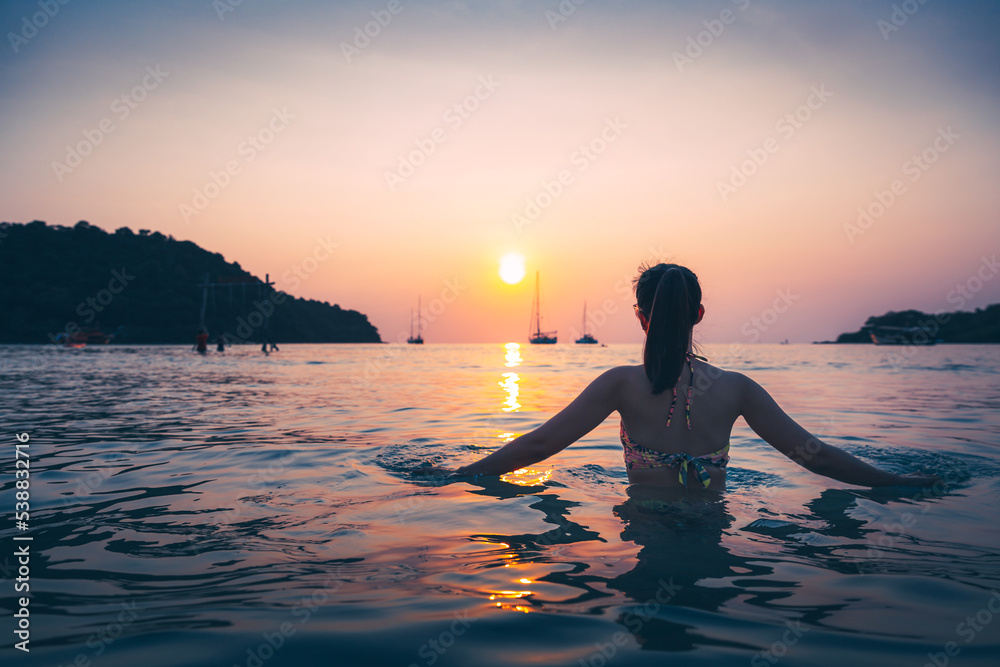 Silhouette of Travel asian woman relax on sea beach in sunset at Thailand