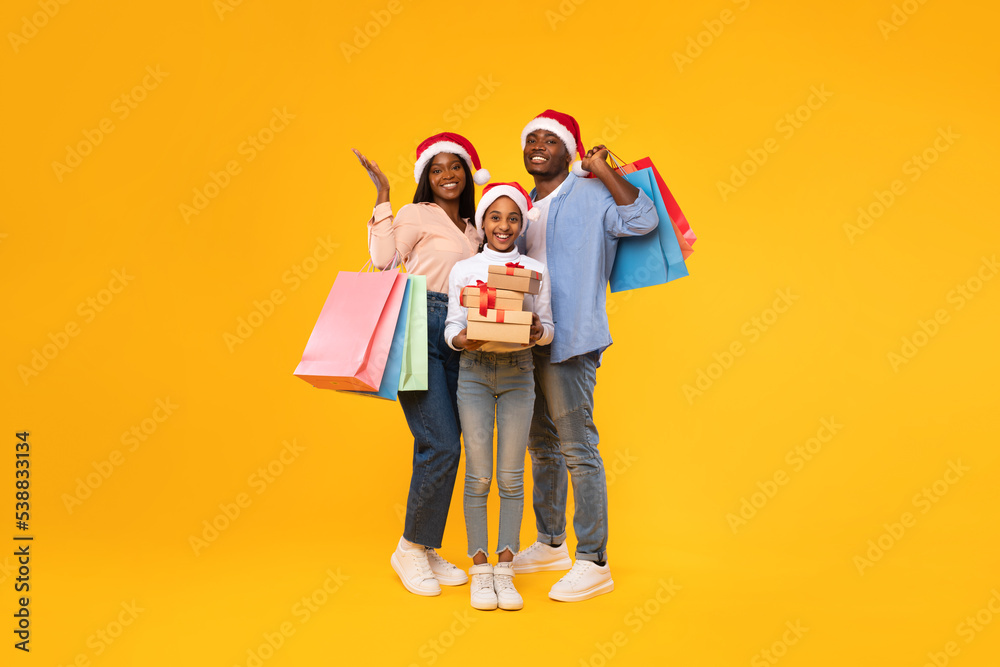 Happy black family holding shopping bags and Xmas gift boxes
