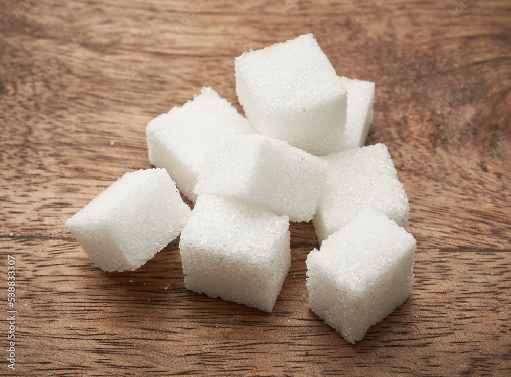 Naklejka premium Kostki białego cukru na rustykalnym tle