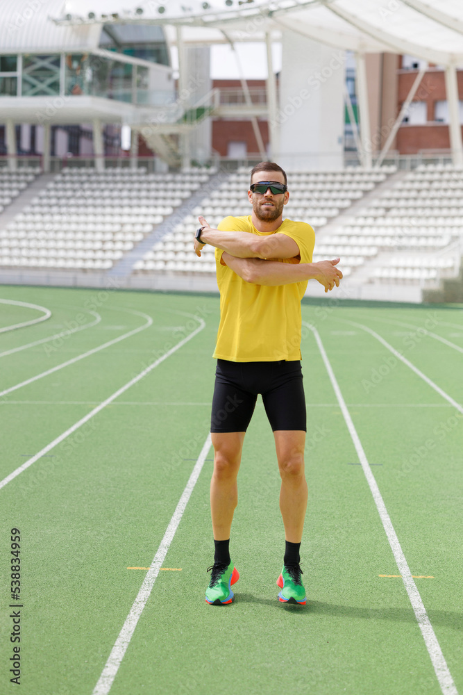 Athlete in sunglasses doing stretching exercise on sports track Athlete in sunglasses doing stretching exercise on sports track