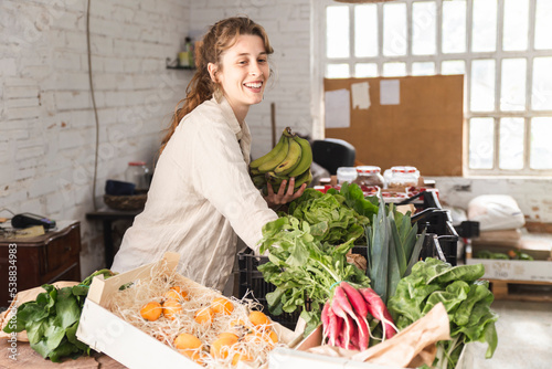 Happy owner picking up vegetables in greengrocer shop photo