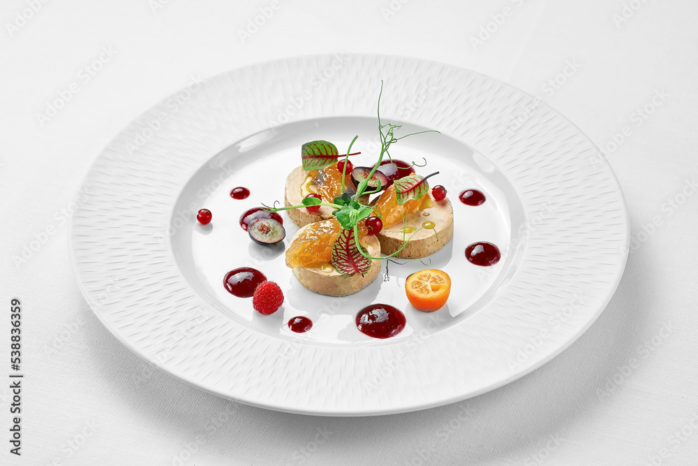 Foie gras with apple confit and berry sauce in a white plate on a white background. Close-up, selective focus. Foie gras with apple confit and berry sauce in a white plate on a white background. Close-up, selective focus.