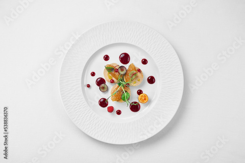 Foie gras with apple confit and berry sauce in a white plate on a white background. Close-up, selective focus.