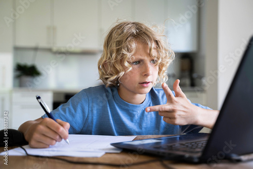 Boy counting through fingers looking at laptop