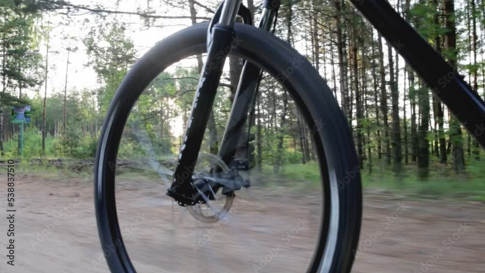 Riding a mountain bike on a forest road against the backdrop of the forest and the rays of the sun. Sports recreation. Outdoor recreation and tourism. Copy space for text, traveling Riding a mountain bike on a forest road against the backdrop of the forest and the rays of the sun. Sports recreation. Outdoor recreation and tourism. Copy space for text, traveling