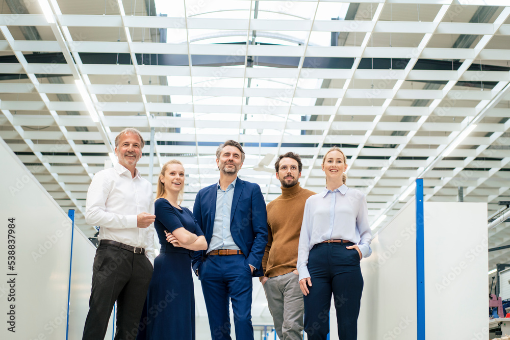 Happy businessman with colleagues standing together at industry Happy businessman with colleagues standing together at industry