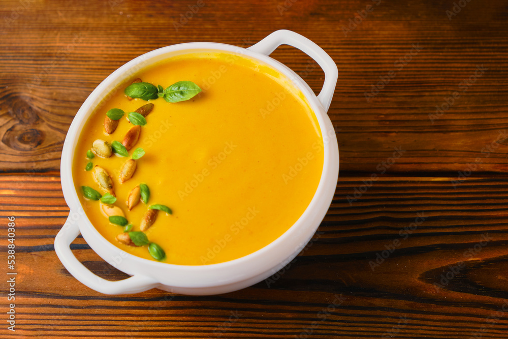 Pumpkin creamy soup in a bowl with seeds and basil Pumpkin creamy soup in a bowl with seeds and basil