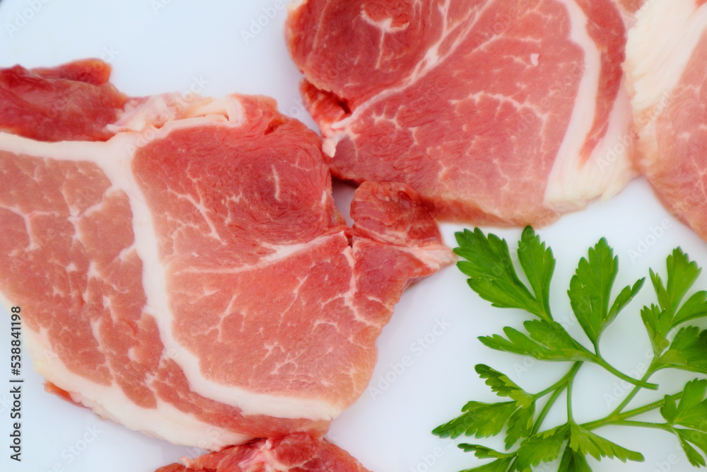 Raw Pork Slice in White Round Plate decorated with parsley. Fresh raw pork. Raw Pork Slice in White Round Plate decorated with parsley. Fresh raw pork.