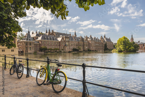 Netherlands, South Holland, The Hague, Bicycles leaning on railing of bridge stretching over Hofvijver lake canal with Binnenhof government office in background photo