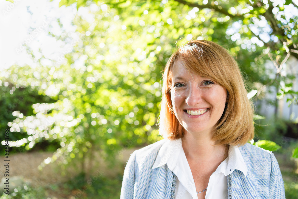 Smiling mature businesswoman in redhead standing in garden Smiling mature businesswoman in redhead standing in garden