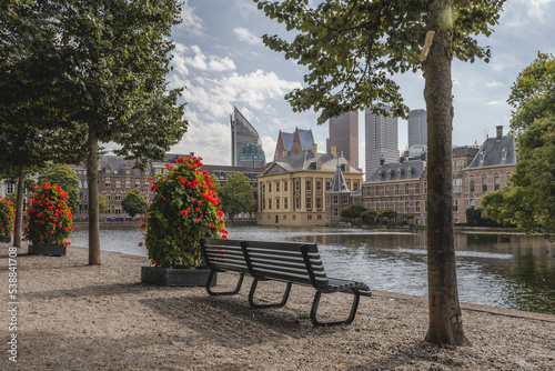 Netherlands, South Holland, The Hague, Park bench in front of Hofvijver lake canal with Mauritshuis museum in background photo